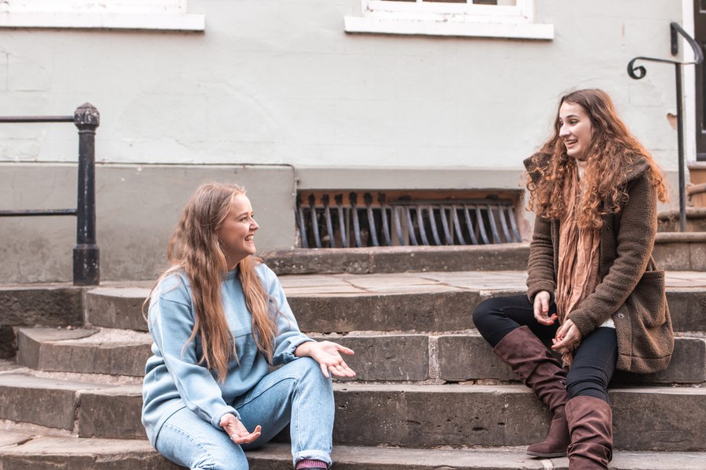 From left to Right Olivia and Casey are sitting on the steps outside and chatting. You can chat to both Olivia and Casey with the link below. 