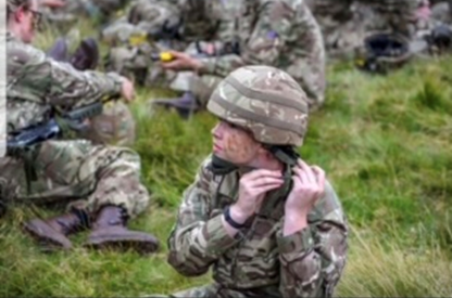 Hannah, in army camo gear, making sure her helmet is tied securely.